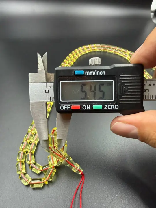 Digital caliper reading 5.45 mm on a finished amber misbaha bead