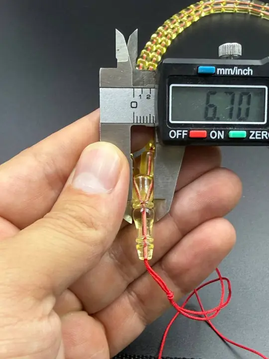 Digital caliper reading 6.70 mm on a finished amber misbaha bead