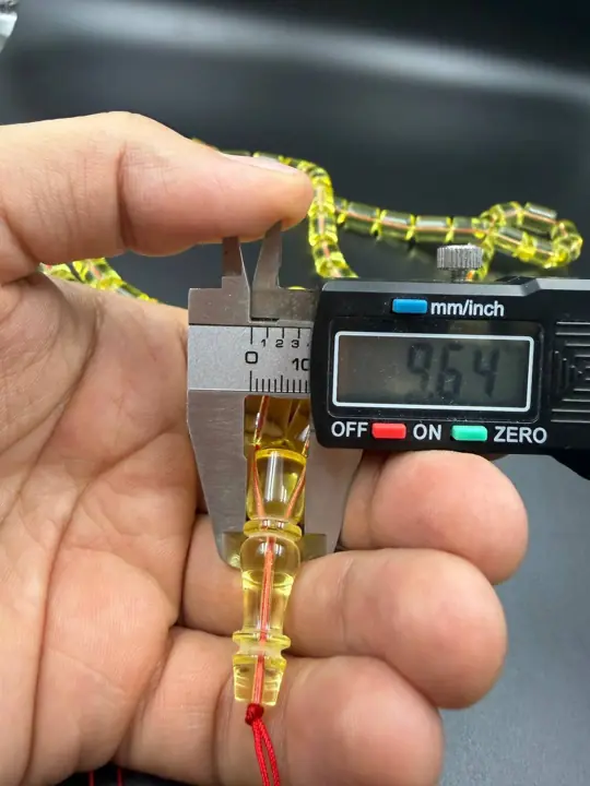 Digital caliper reading 9.64 mm on a finished amber misbaha bead