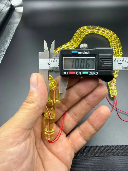 Digital caliper reading 10.06 mm on a finished amber misbaha bead
