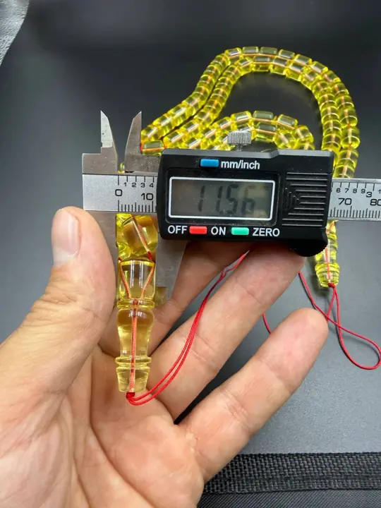 Digital caliper reading 11.56 mm on a finished amber misbaha bead