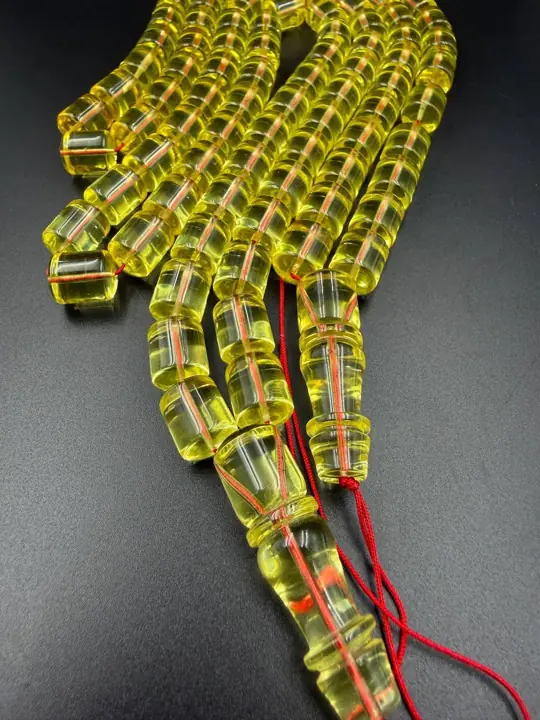 Three-quarter — finished transparent amber misbaha strand photographed in the VIAMBER atelier
