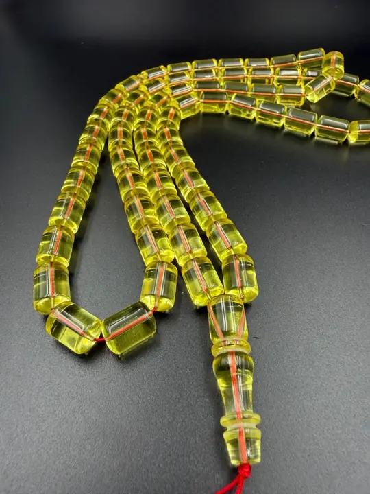 The fall — finished transparent amber misbaha strand photographed in the VIAMBER atelier